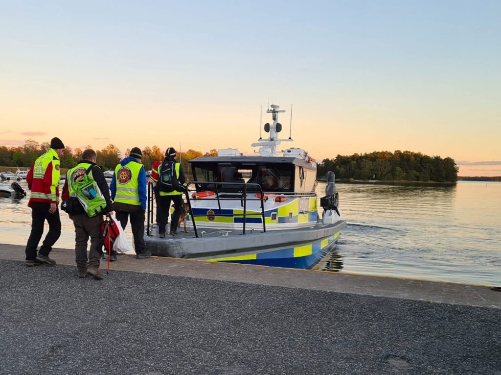 Polisbåt i vattnet med personer som går på båten.